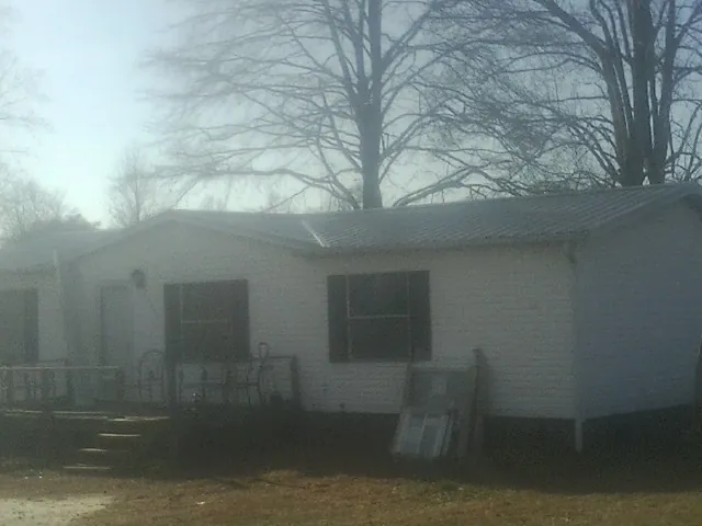 New metal roof on a white painted brick home on a foggy morning in Clayton